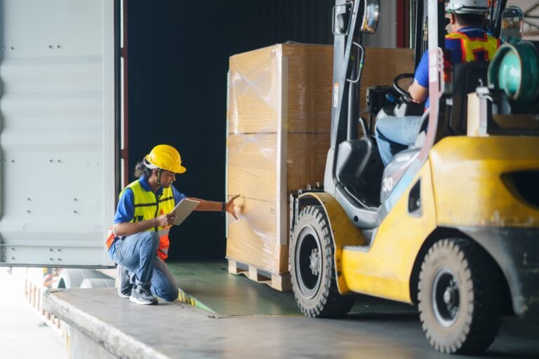 Asian forklift driver loading a shipping cargo container with a